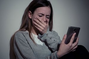 Mädchen hält weinend ihr Smartphone in der Hand