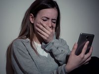 Mädchen hält weinend ihr Smartphone in der Hand