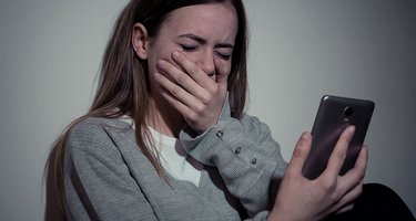 Mädchen hält weinend ihr Smartphone in der Hand