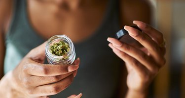 Junge Frau zeigt Glas mit medizinischem Cannabis