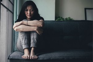 Einsame, traurige Frau kauert auf dem Sofa