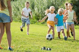 Sechs Kinder spielen Fu&szlig;ball auf einer Wiese